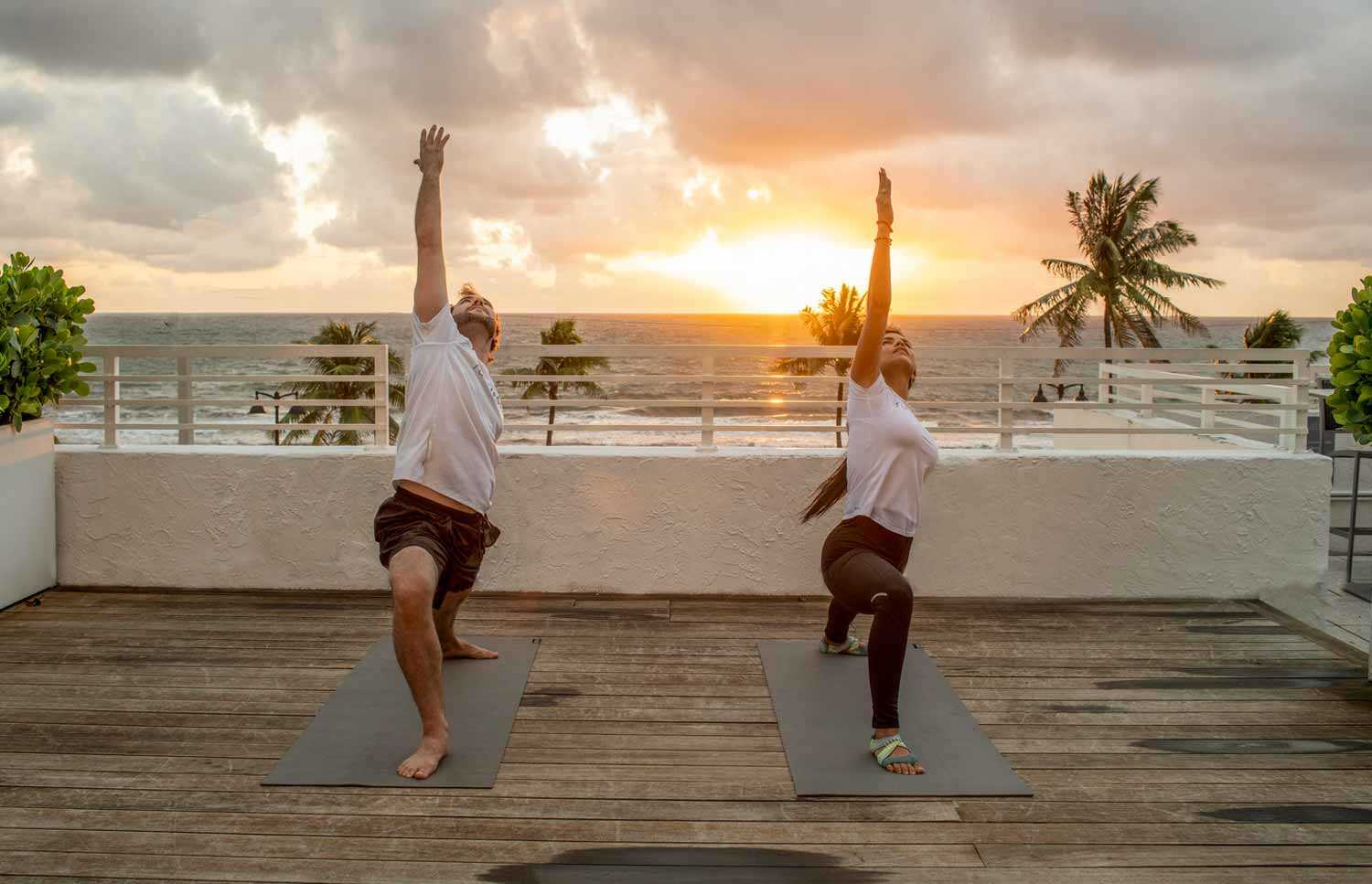man and woman doing yoga during sunset