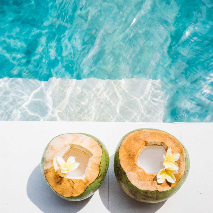 two open green coconuts on edge of pool