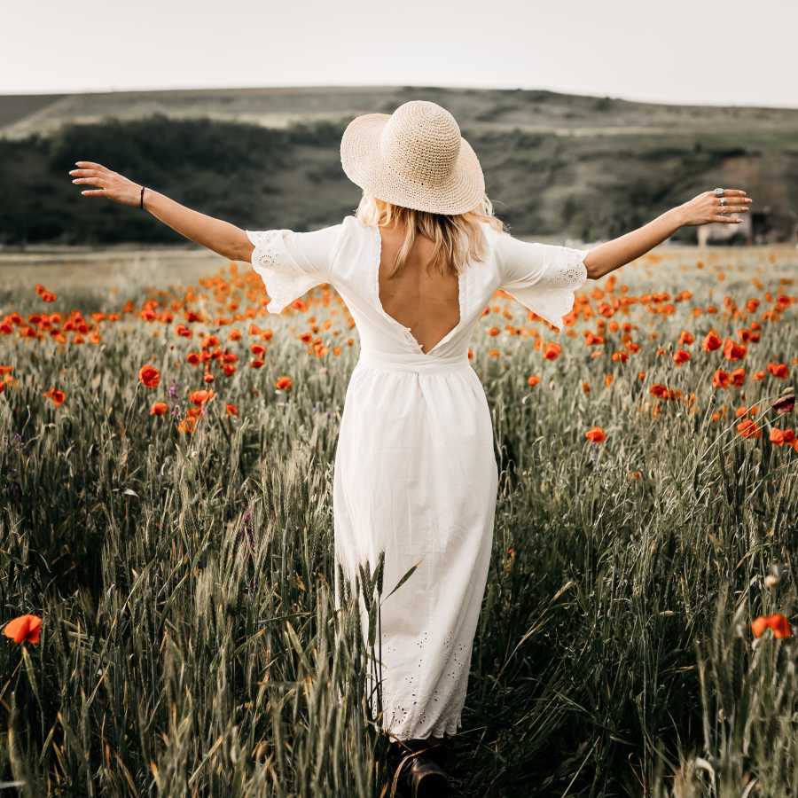 woman walking with arms outstretched in a field of flowers