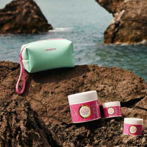 lotions and bag on a rock with the ocean in the background