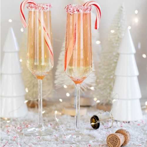 two filled champagne flutes garnished with candy canes