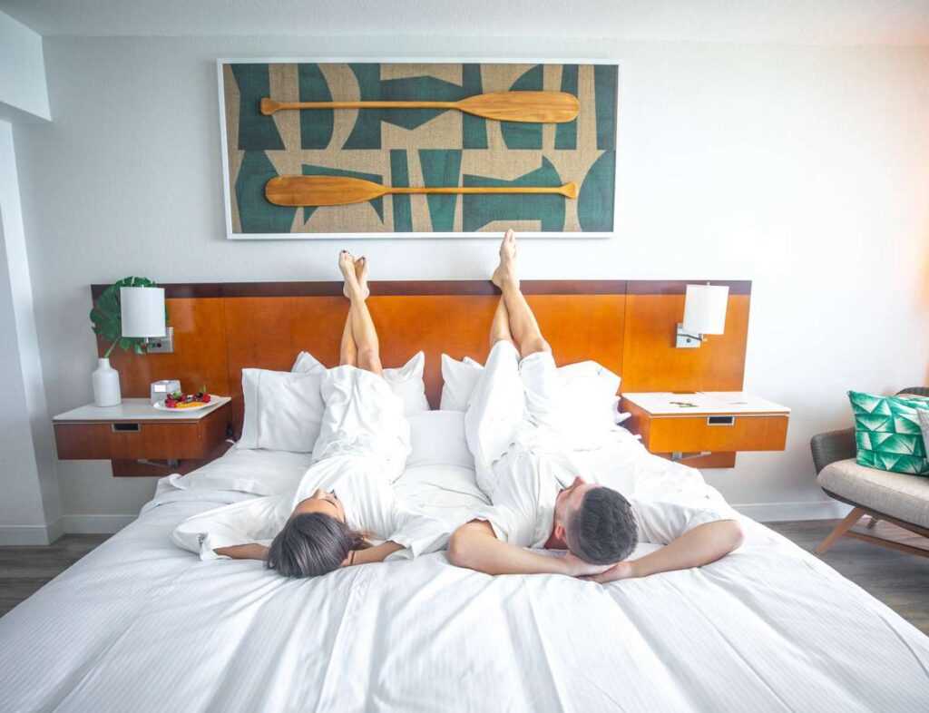 a man and woman lying on a bed in bathrobes with their feet on the headboard
