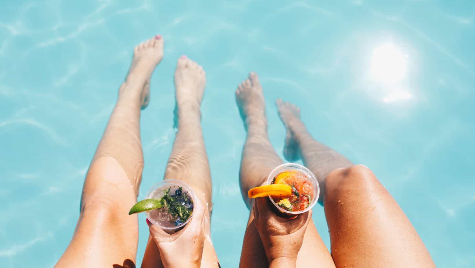 two people sitting in a pool with drinks