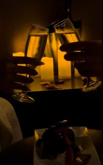 two champagne glasses being clinked by candlelight