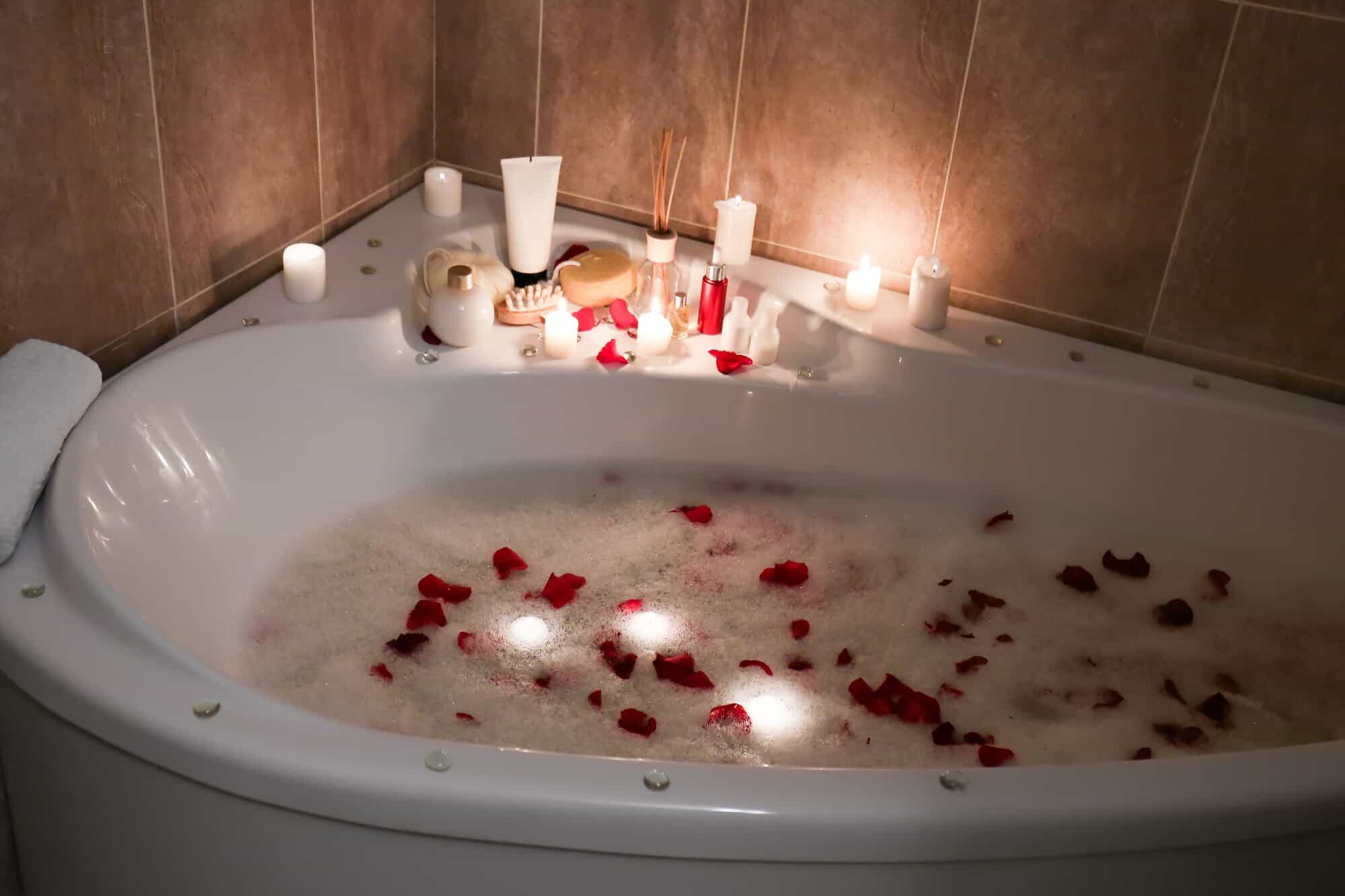 a bathtub with candles and rose petals